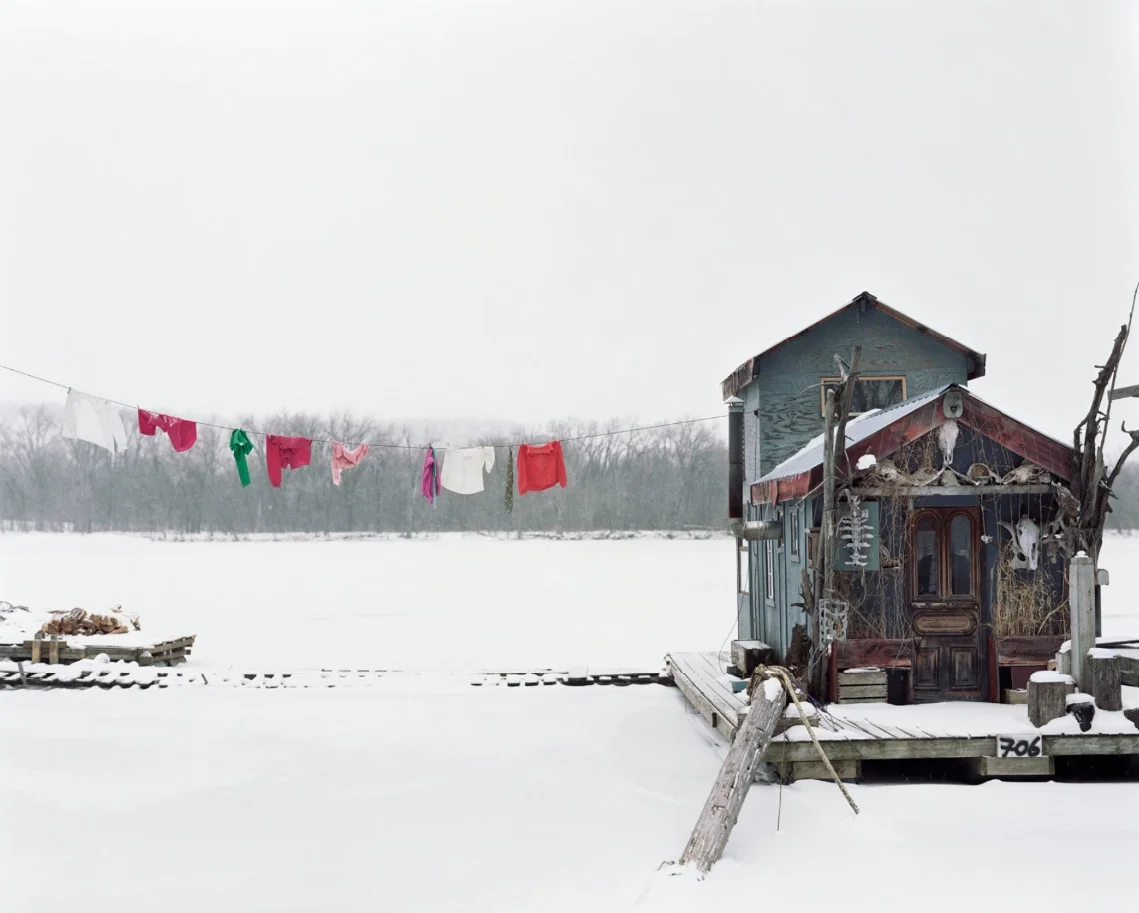 Weathered boathouse on frozen lake with colorful laundry drying outdoors