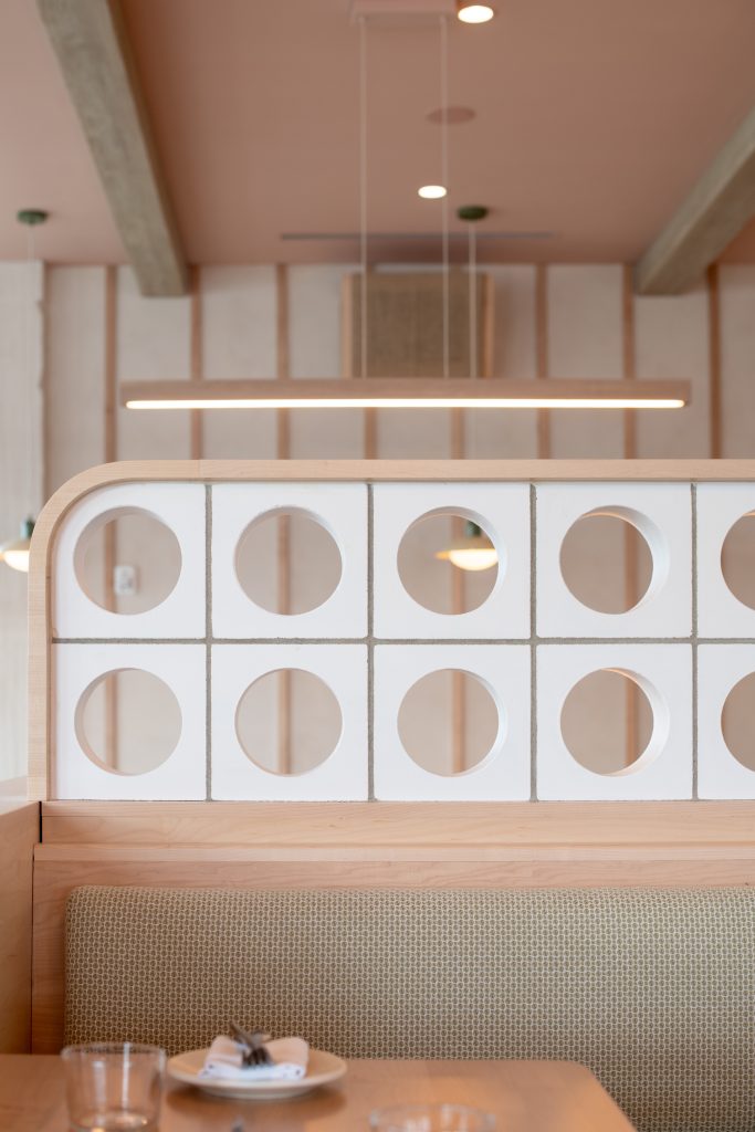 Modern restaurant interior with circular window display and linear pendant lighting