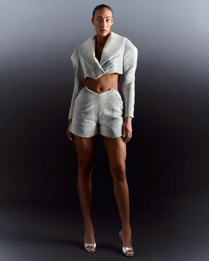 Woman wearing white cropped blazer and shorts ensemble, studio portrait