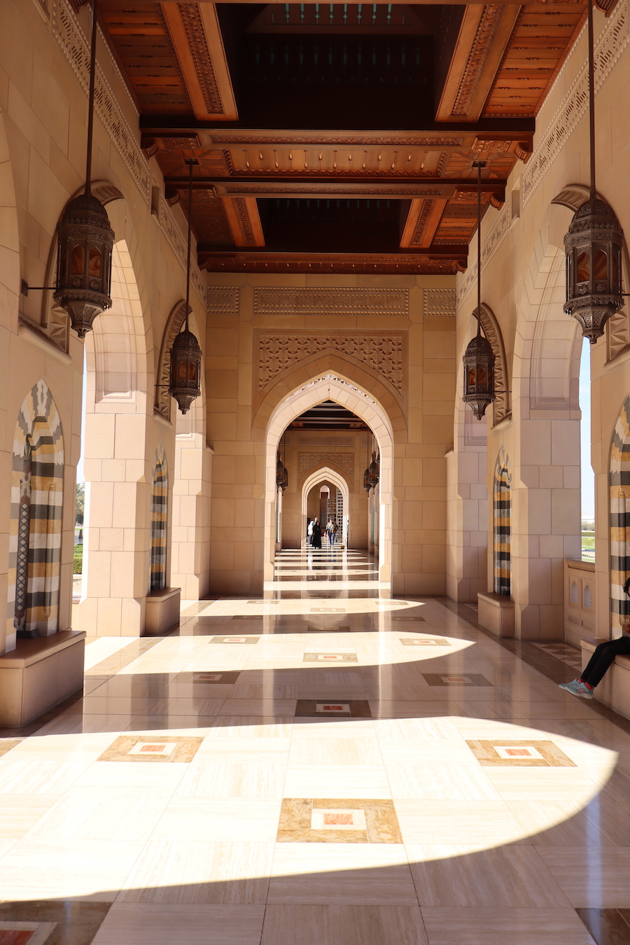 Islamic architecture corridor with ornate arches and hanging lanterns