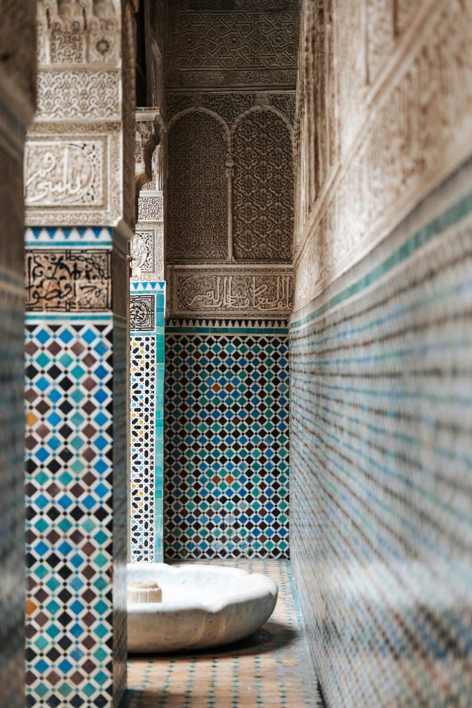 Ornate Islamic architectural corridor with intricate zellige tilework and carved plaster details