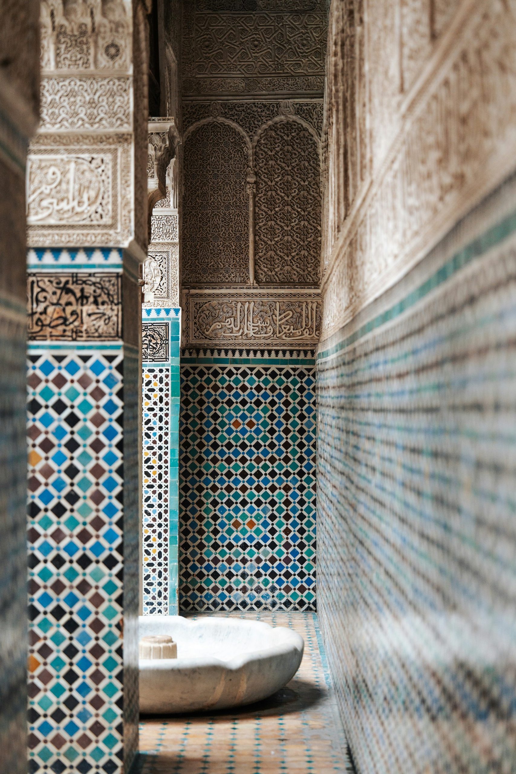 Ornate Islamic architectural corridor with intricate zellige tilework and carved plaster details