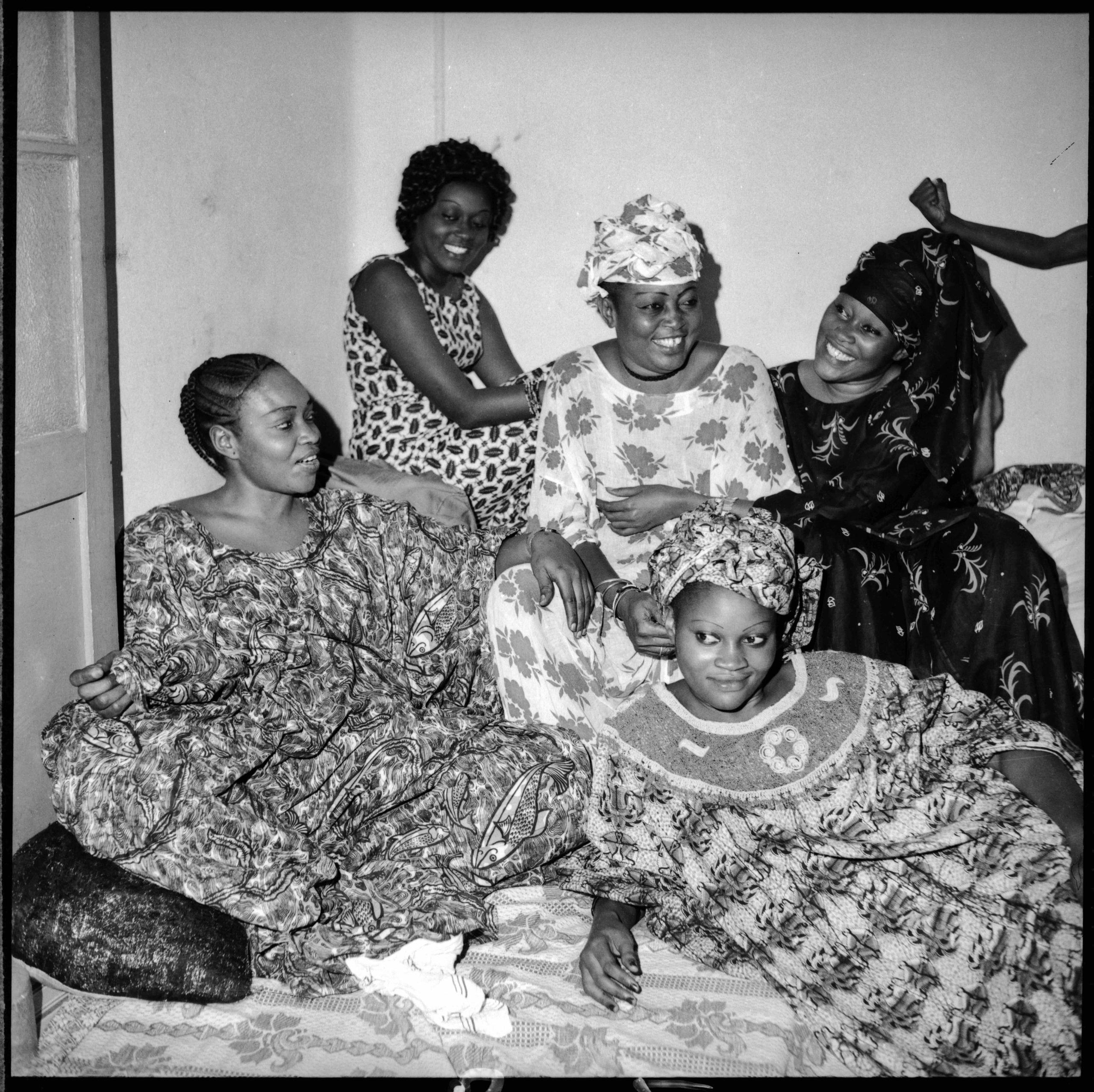 Black and white photograph of six African American women gathered together indoors, smiling.
