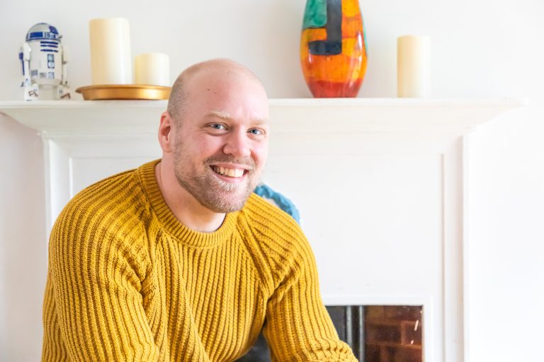 Smiling man wearing mustard yellow ribbed sweater in modern home interior