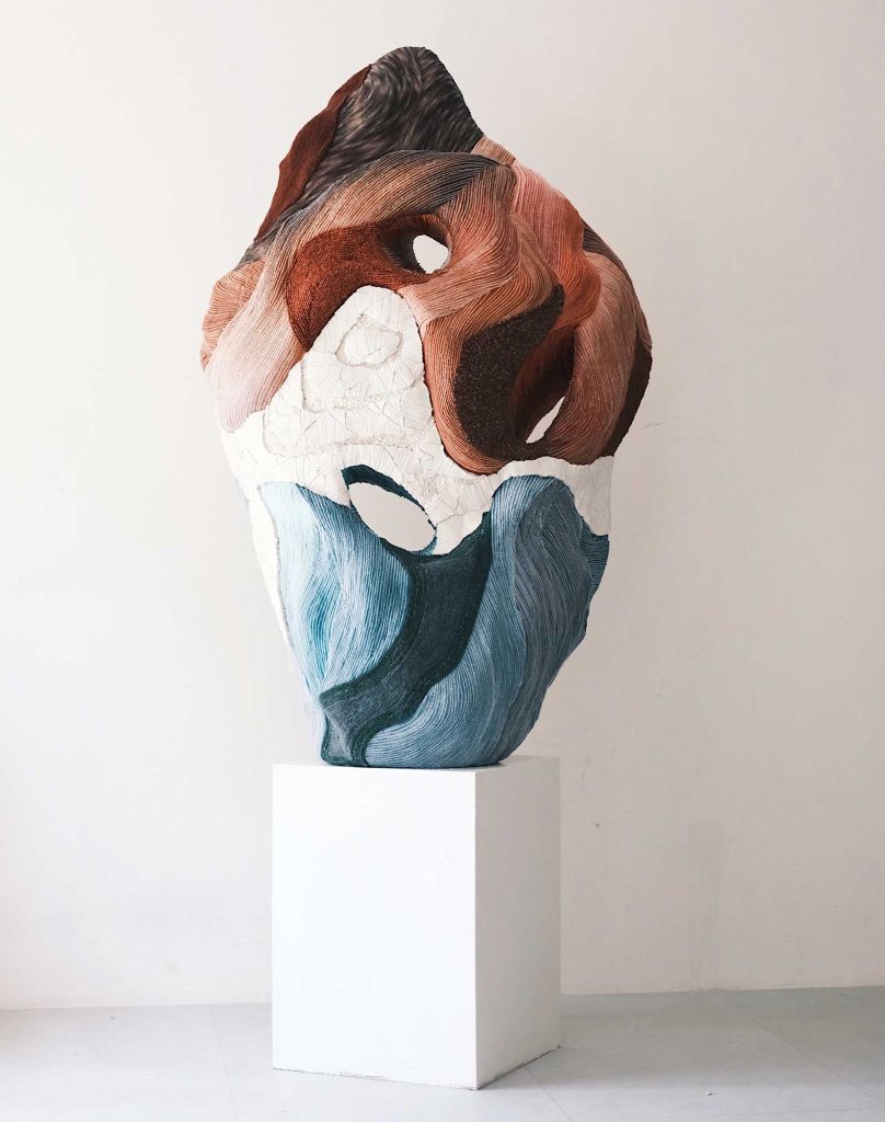 vertical, multicolored sculpture made of textiles and other materials