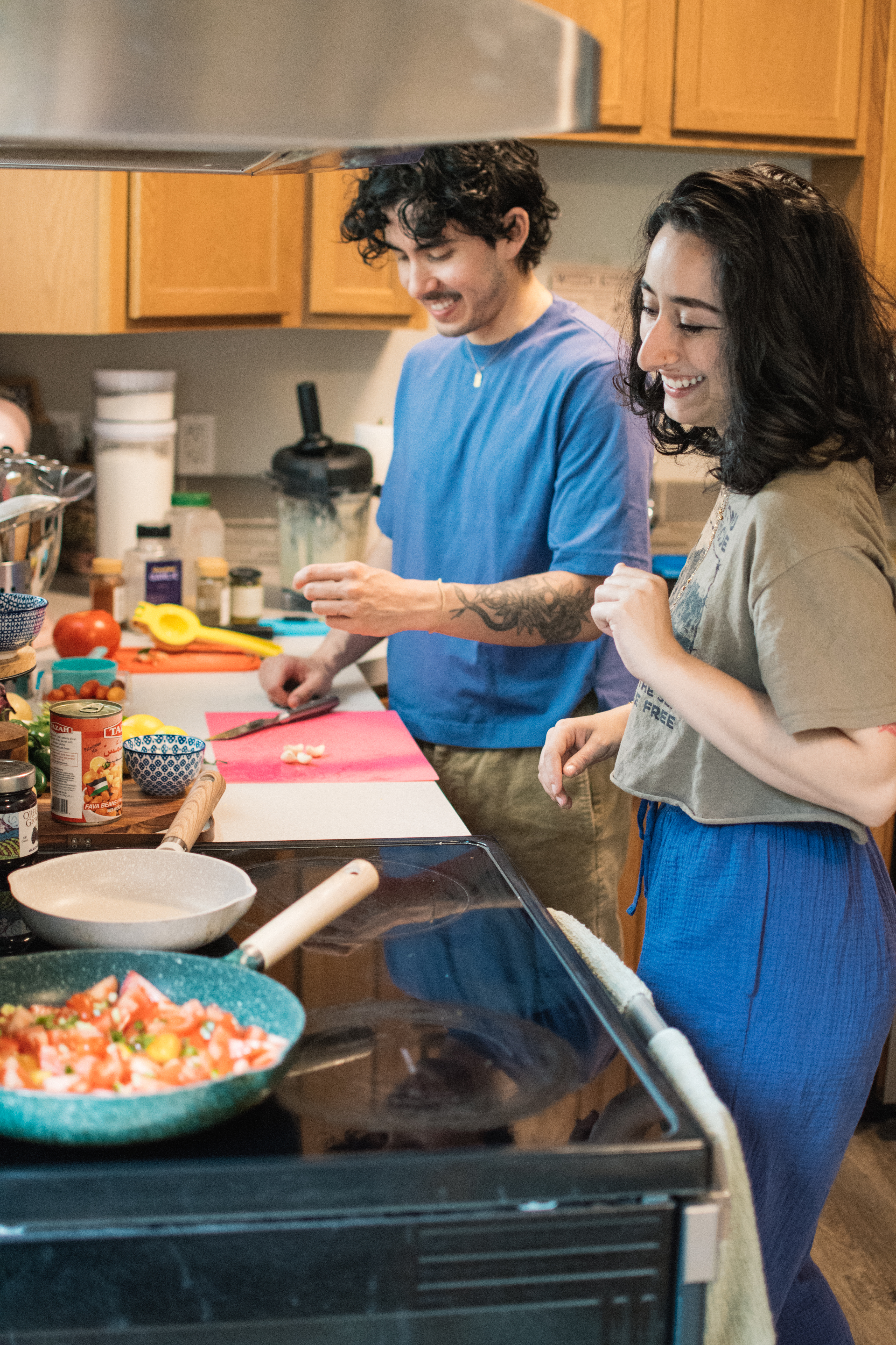 Image of two people smiling and cooking in a kitchen