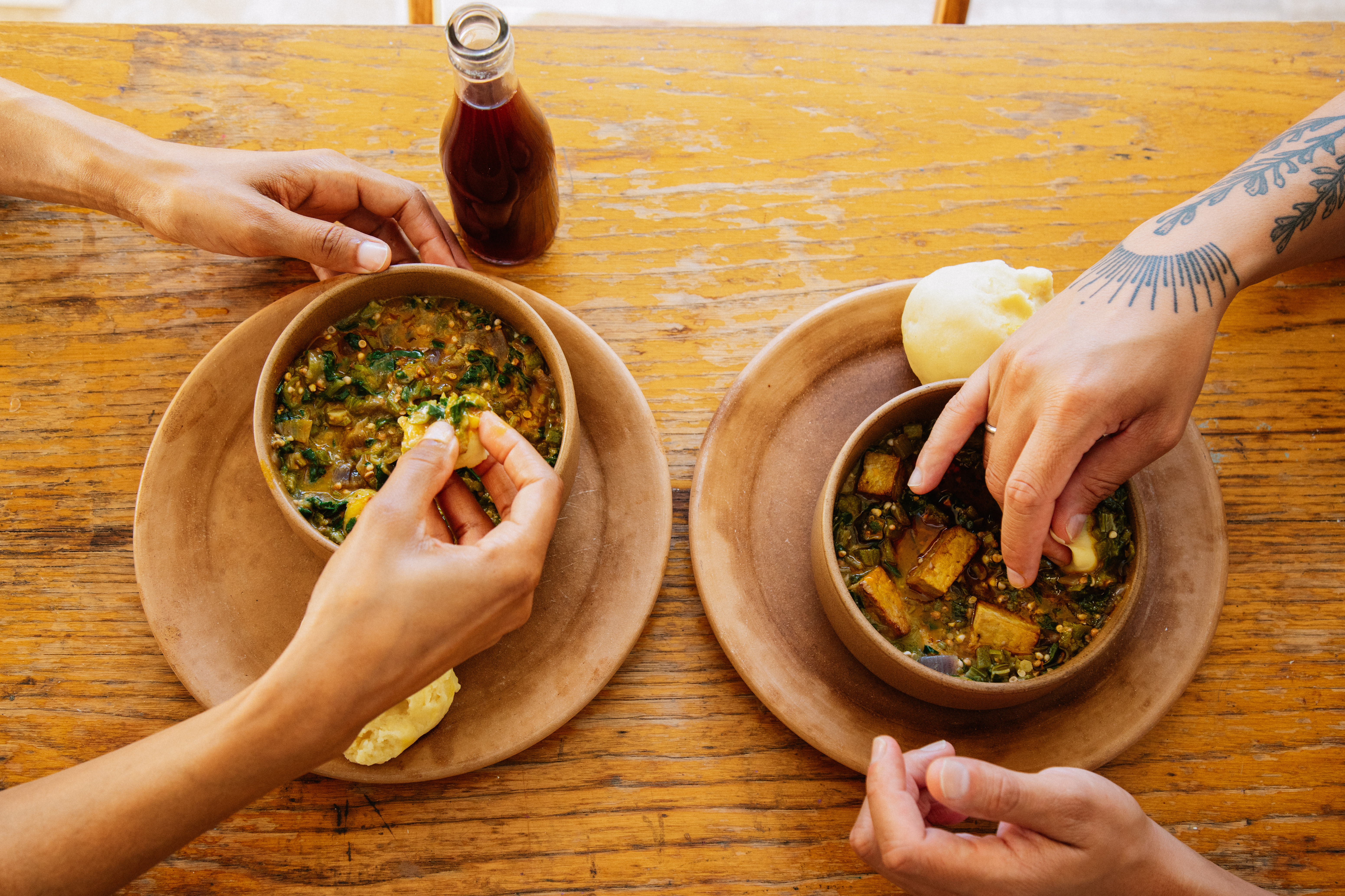 Overhead image of two pairs of hands in bowls at a dining table