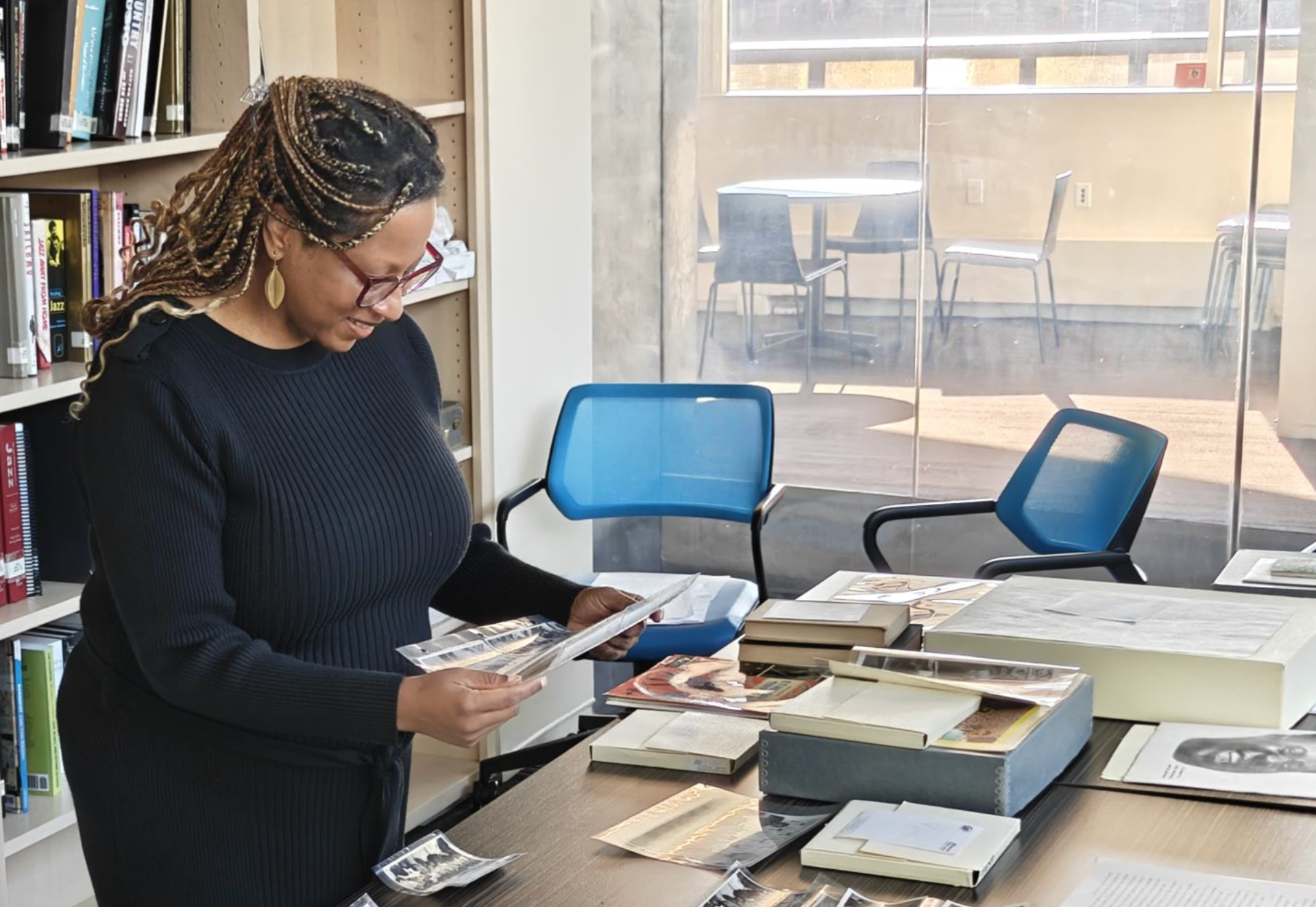 image of Black woman, with braided hair, sort through photographs at a desk